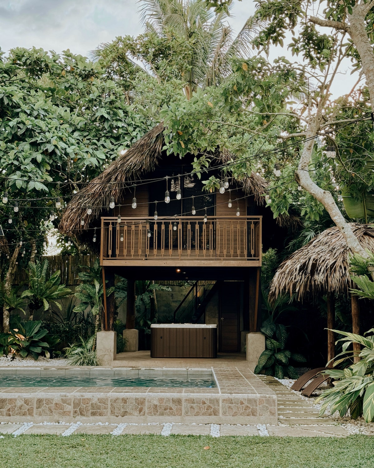 Beladi Villas thatched two-story villa with balcony surrounded by tropical plants